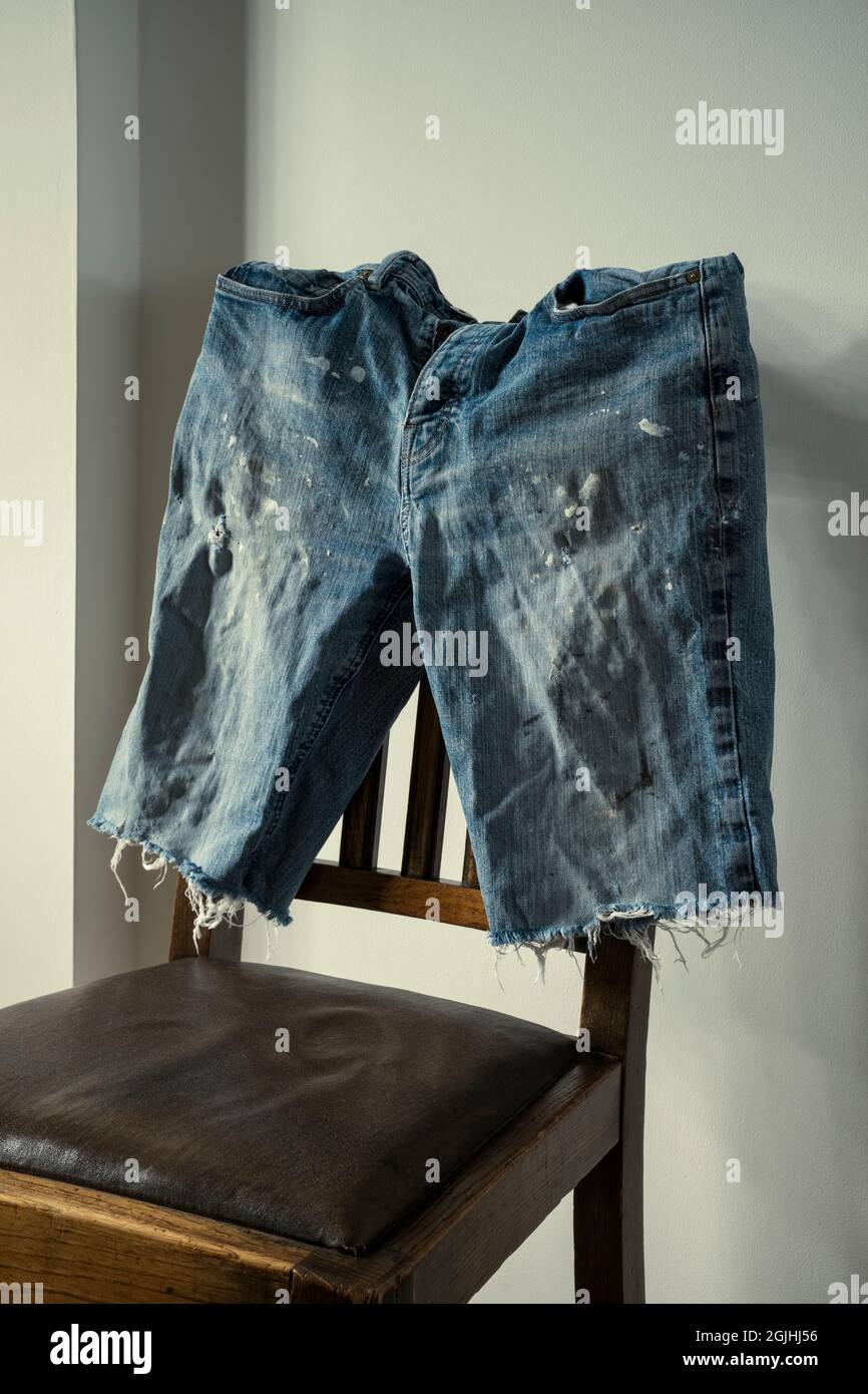 Old denim shorts on a wooden chair. Stock Photo
