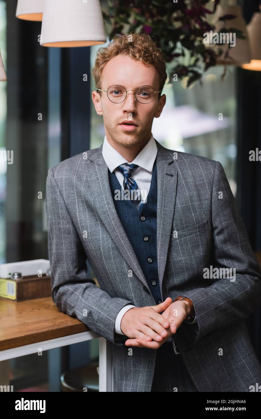 confident young businessman in formal wear and glasses looking at ...