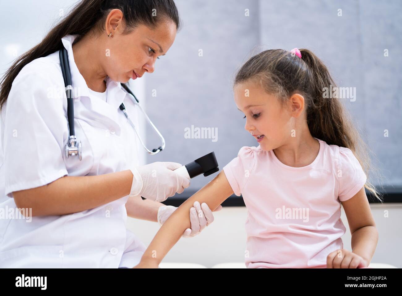 Medical Doctor Examining Child Doctor Using Dermatology Device Stock