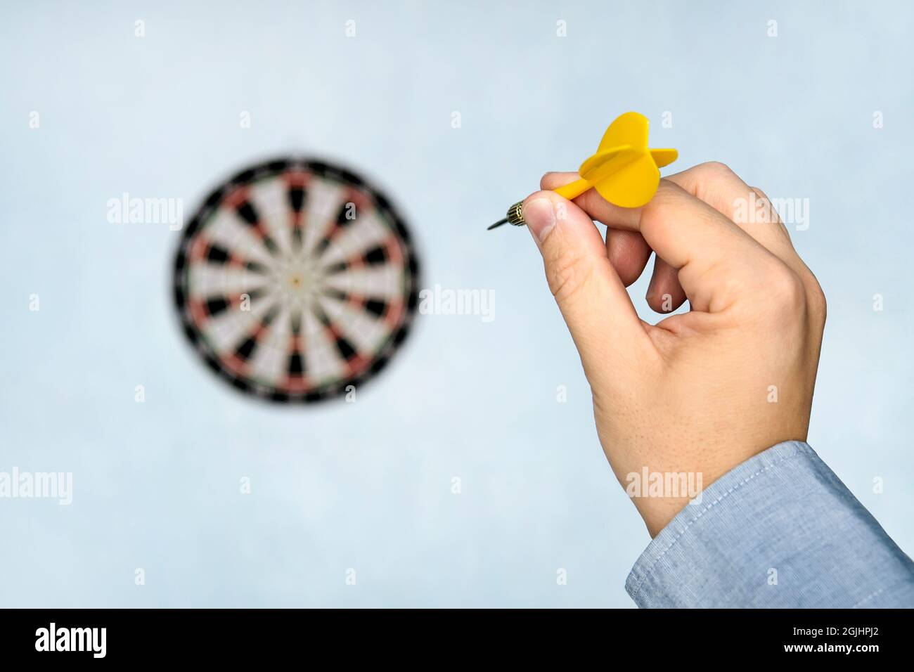 A hand holding a dart getting ready to aim at the dartboard on blue