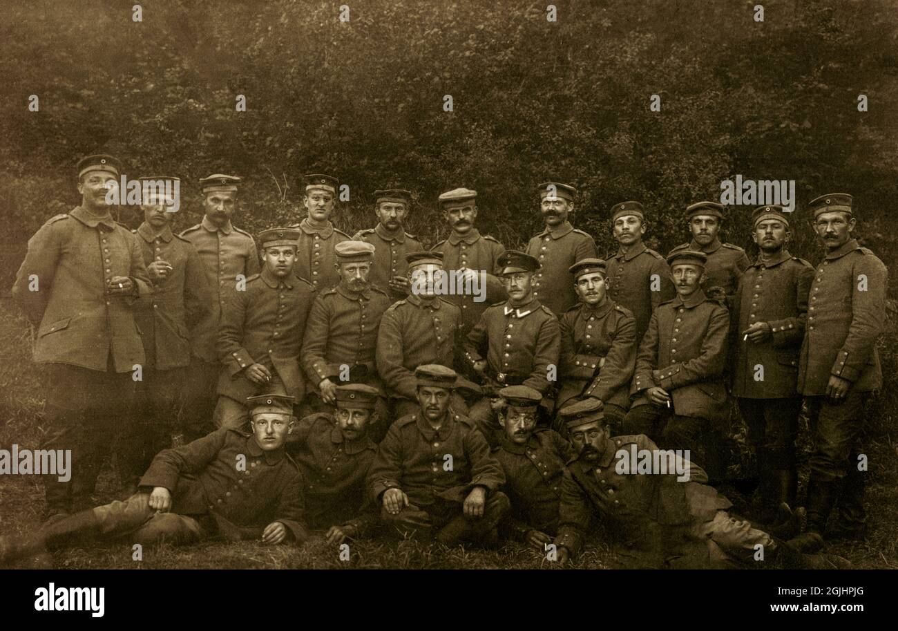 Group of 1914-18 First World War Imperial German Army soldiers pose with their officer (middle row, peaked cap) for a portrait. The 21 infantrymen wear buttoned tunics and forage caps, with many holding cigarettes.  The number ‘118’ is just visible on some of the men’s shoulder boards, signifying that they belonged to Infantry Regiment 118 (Infanterie Regiment Prinz Carl Nr. 118),  part of the 56th Infantry Division that suffered heavy losses fighting from 1915 to 1918 on both Eastern and Western Fronts in battles such as those at Verdun, the Somme and Arras. Stock Photo