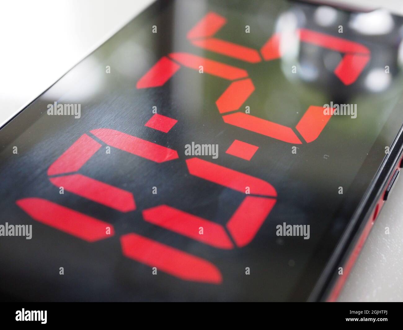 Close-up of a mobile phone screen with the display showing a digital time readout Stock Photo