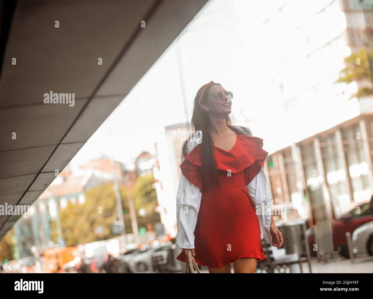 A stylish woman in a red dress walking down the street Stock Photo - Alamy