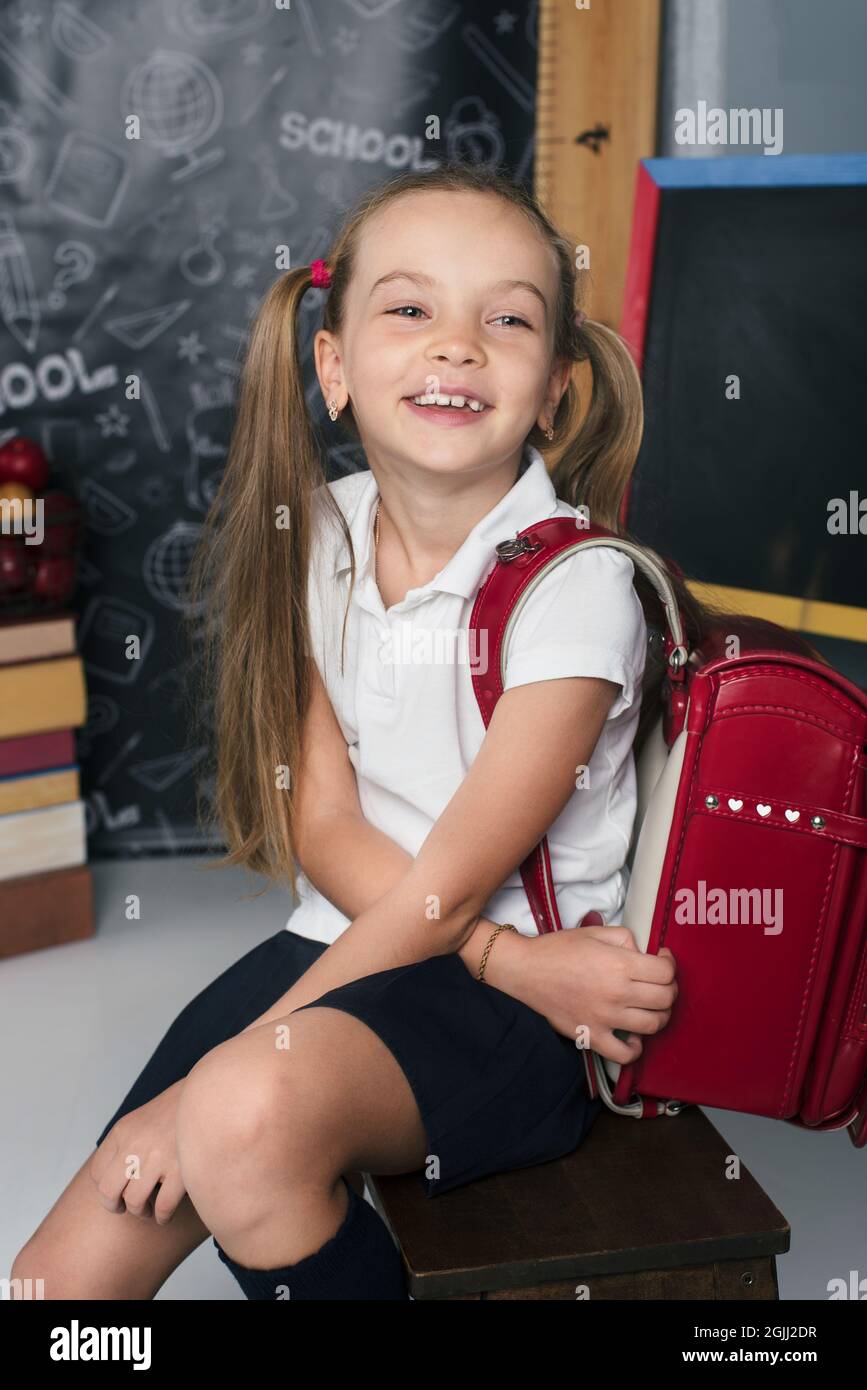 Happy schoolchild in the classroom with big backpack and positive emotions. Excieted and ready to study girl Stock Photo