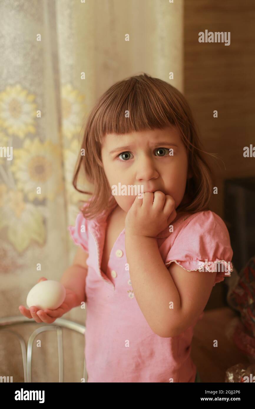 Little girl wearing a pink T-shirt with a frightened expression. Stock Photo