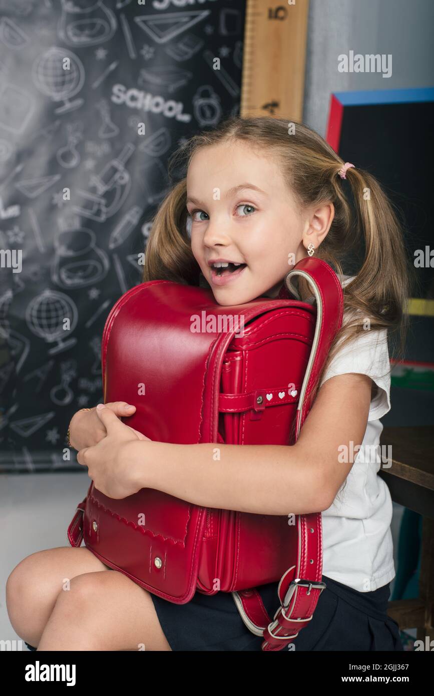 Happy schoolchild in the classroom with big backpack and positive emotions. Excieted and ready to study girl Stock Photo