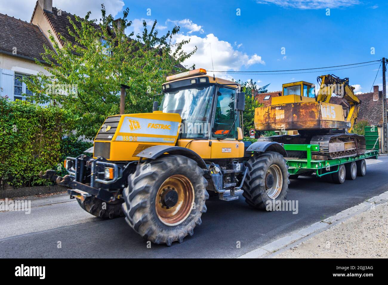 JCB Fastrac 185-30 4-wheel drive agricultural tractor towing mechanical digger on trailer - Ciron, Indre (36), France. Stock Photo