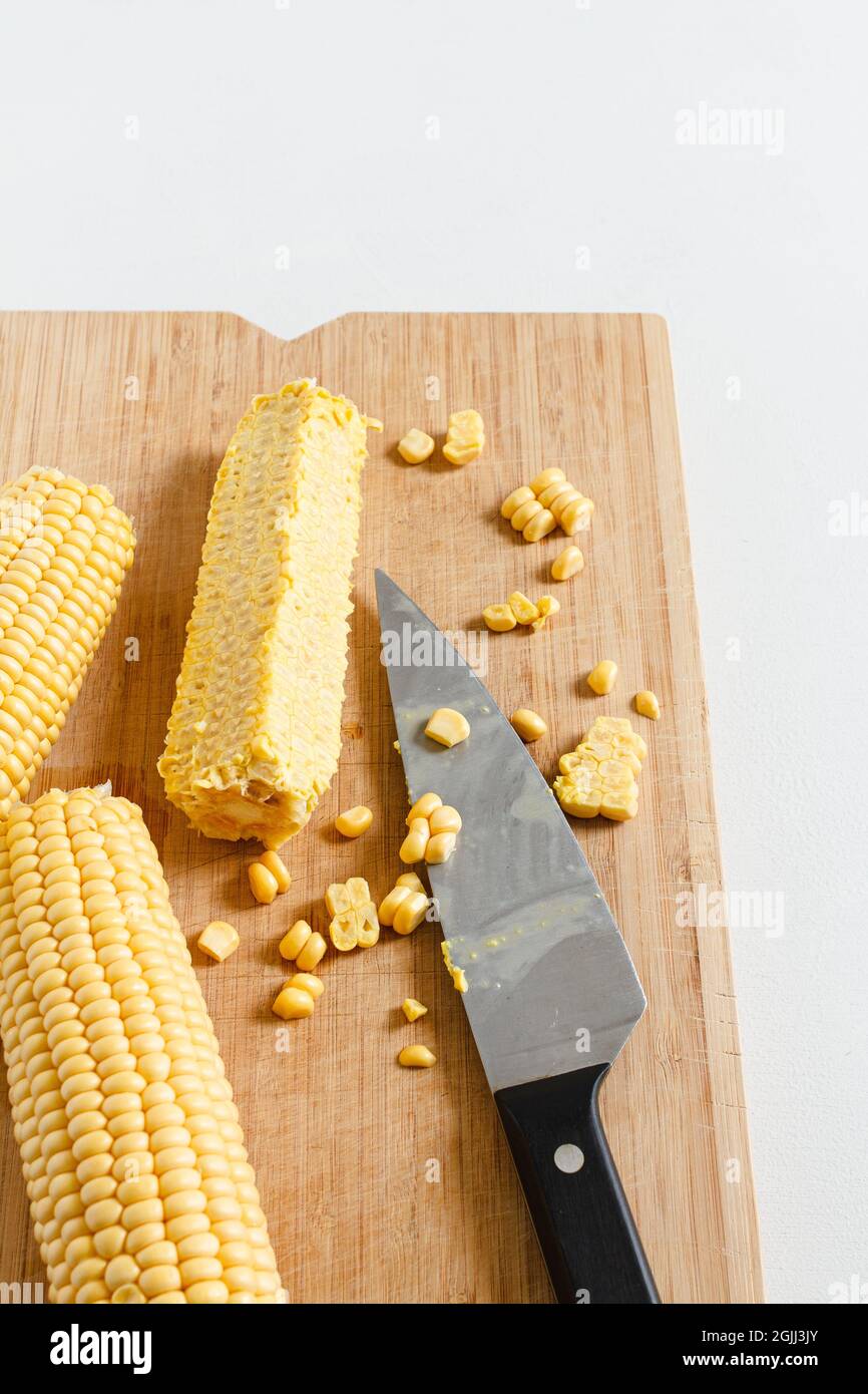 Chopping corn cobs on a wooden board. Stock Photo