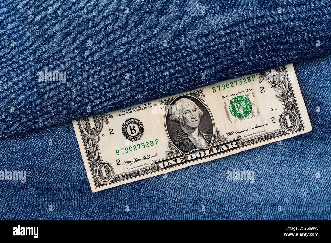 Money and fashion. One dollar bill on a denim jeans background. Concept