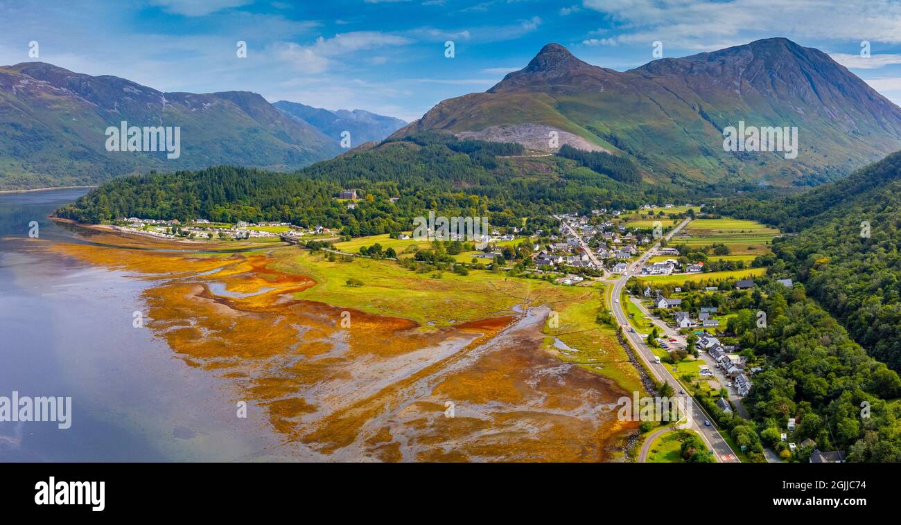 Aerial view from drone of Sgorr na Ciche or the Pap of Glencoe and village of Invercoe (left) and Glencoe village beside Loch Leven in Glen Coe , Loch Stock Photo