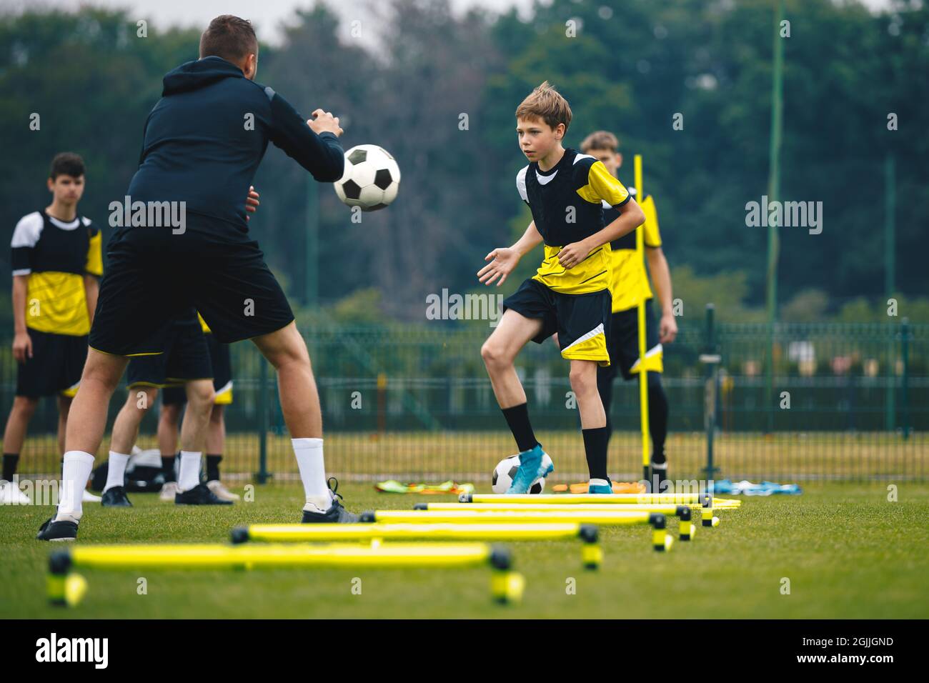 Teenagers on soccer training camp. Boys practice football with young