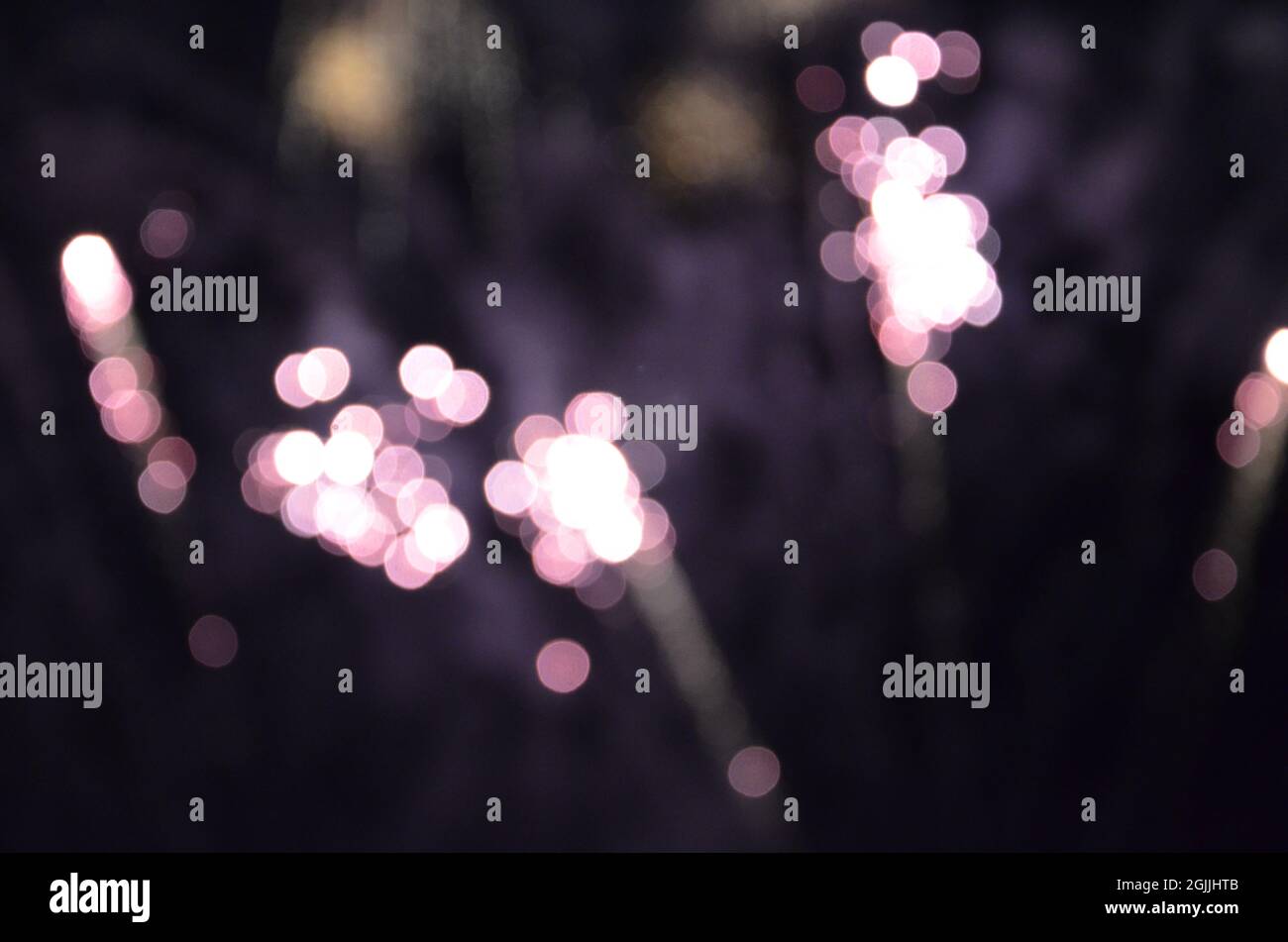 Purple light bokeh created by fireworks against dark sky Stock Photo