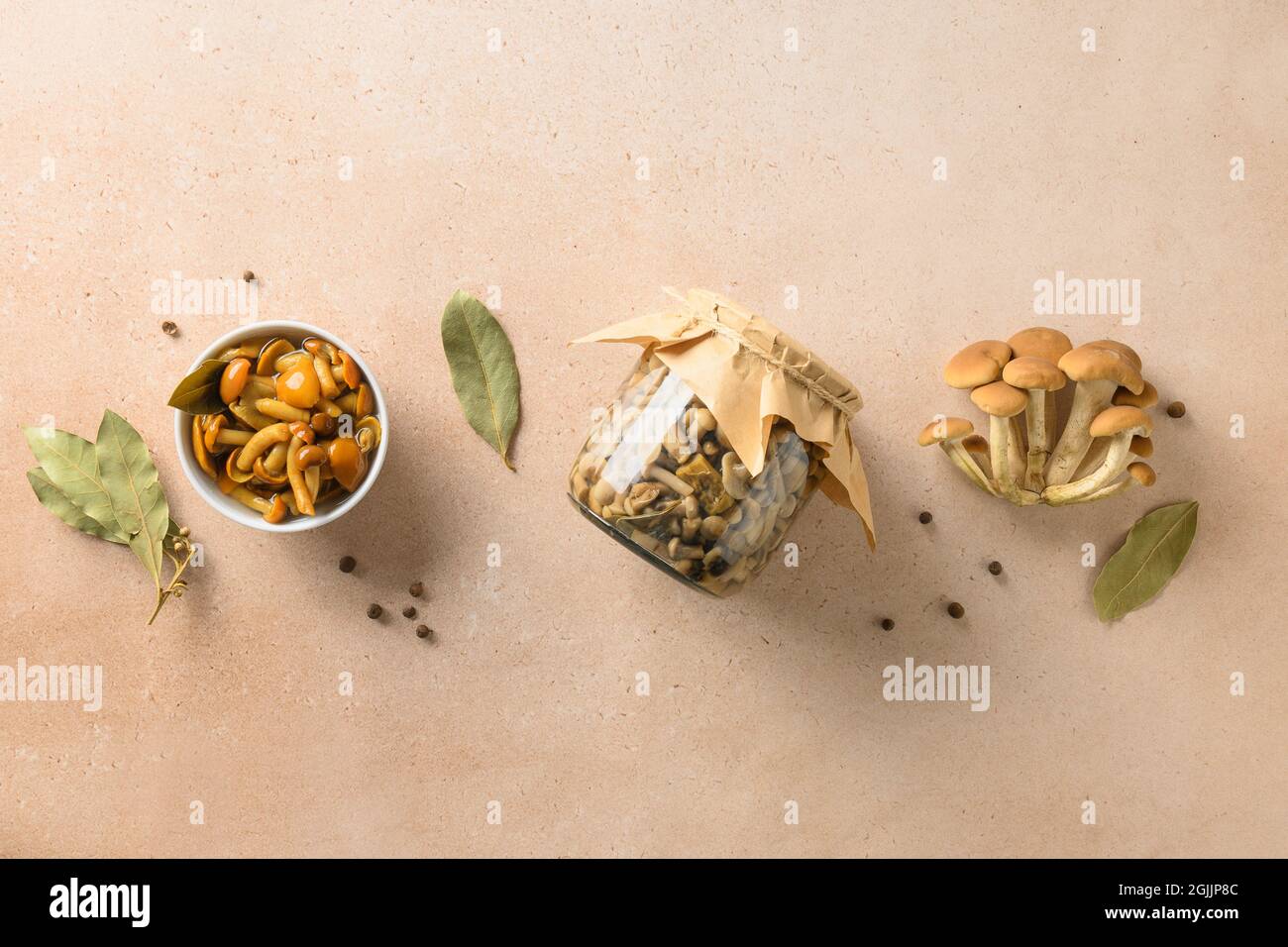 Pickled honey mushrooms served in bowl with bay leaf and spices. View