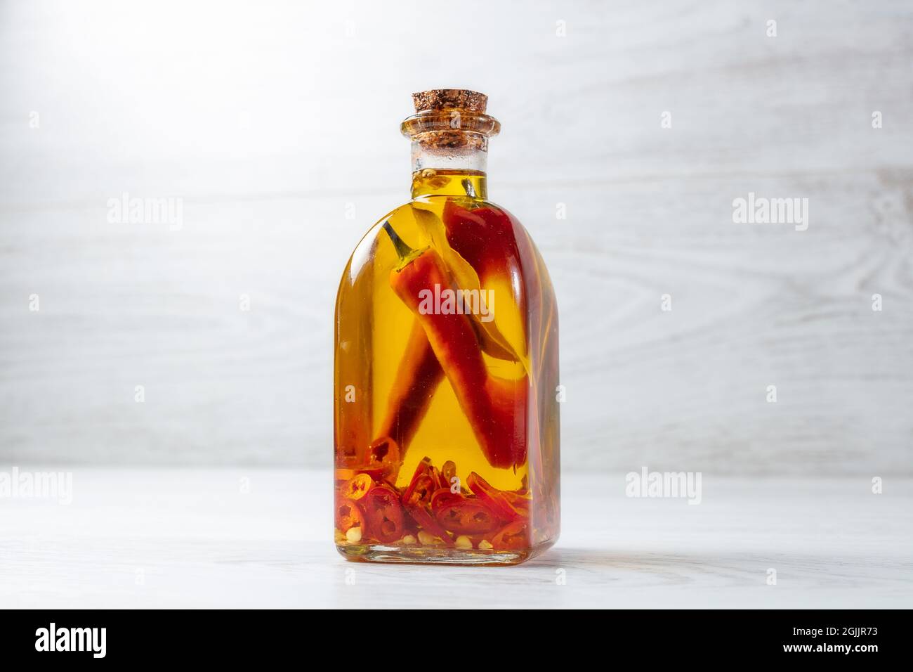 Spicy jar with chilli isolated on wooden background. Stock Photo