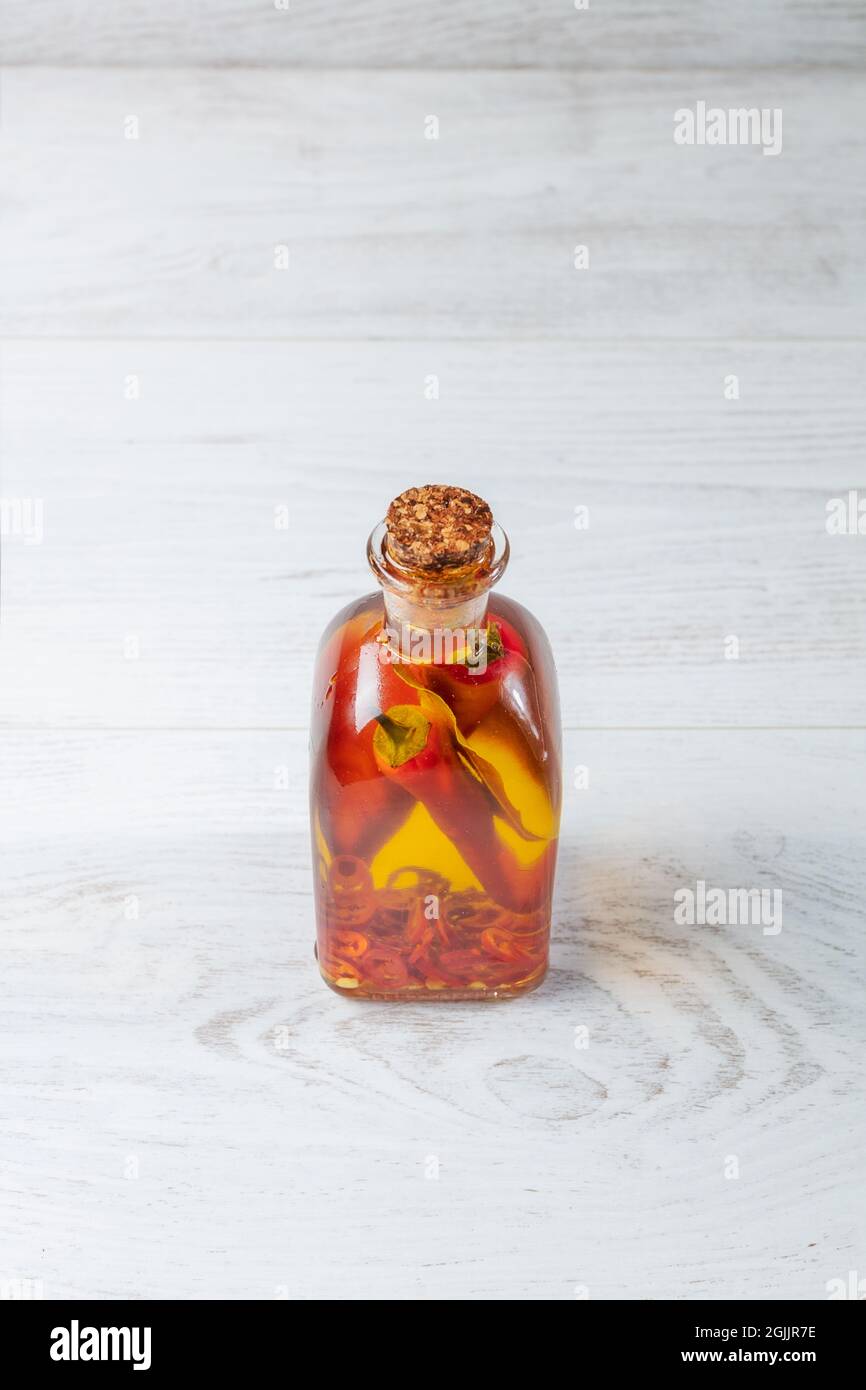 Spicy jar with chilli isolated on wooden background. Stock Photo