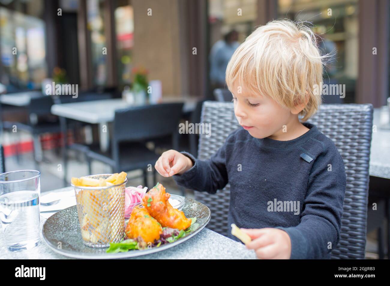 Preschool child, cute boy, eating fish and chips a restaurant, cozy atmosphere, local small restaurant in Stockholm, Sweden Stock Photo