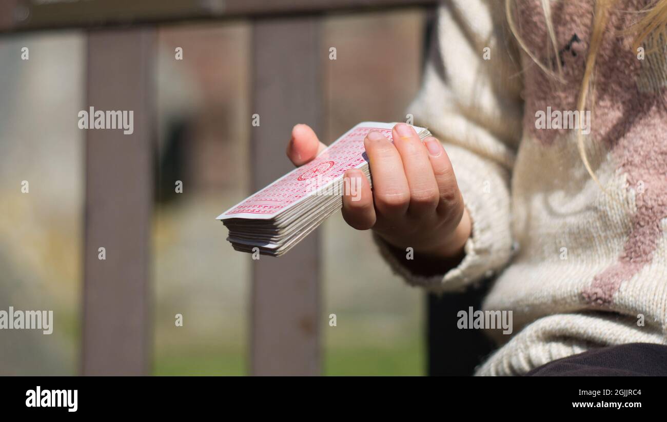 Closeup shot of a blonde hair little girl hand keeping a deck of playing cards Stock Photo