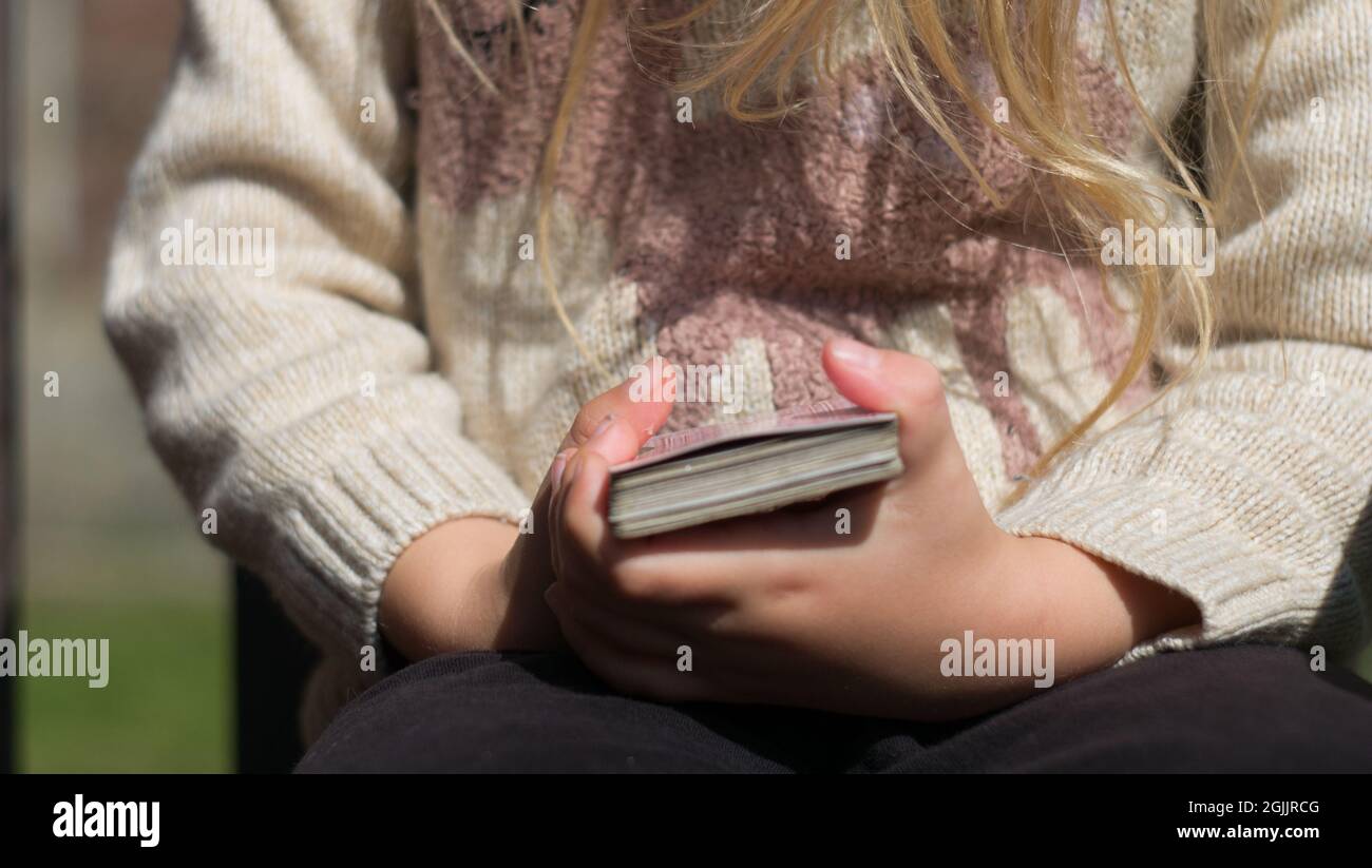 Closeup shot of blond hair little girl hands keeping a deck of playing cards in her hands Stock Photo