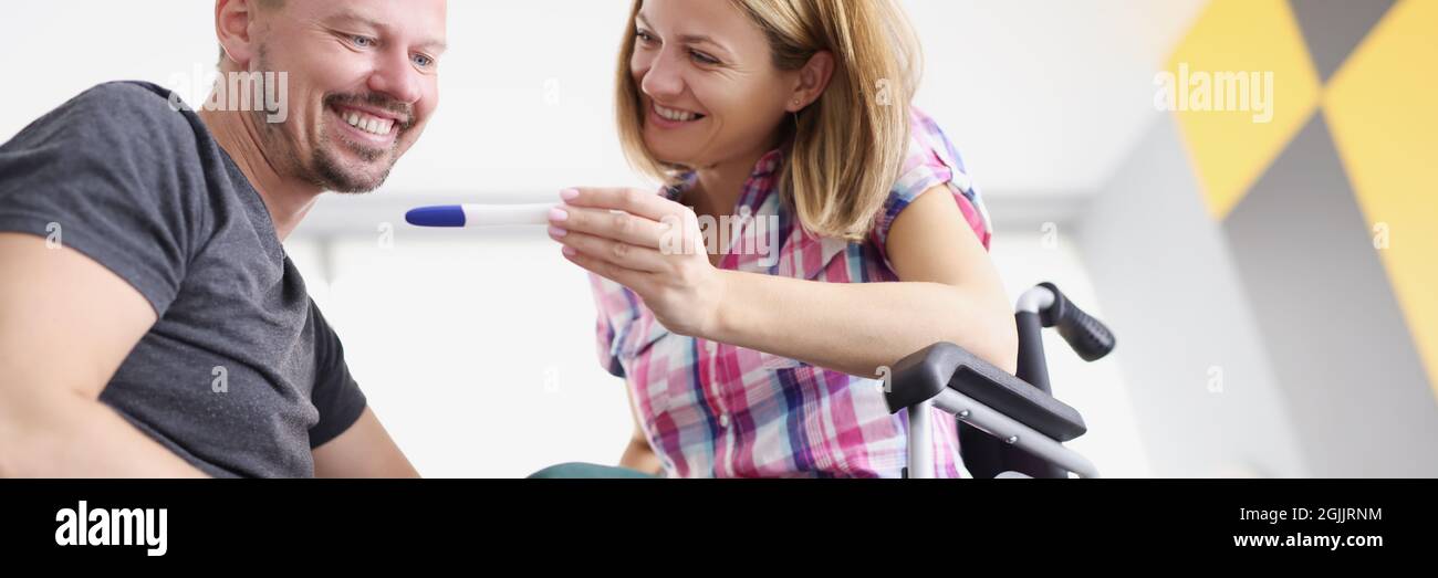 Happy woman in wheelchair showing pregnancy test to her husband Stock