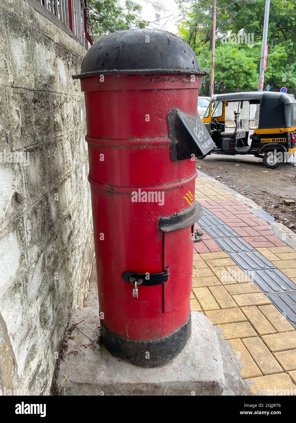 A vintage red colored post box also called letter box standing vertical besides a wall at Pune India on 7 July 2021 Stock Photo