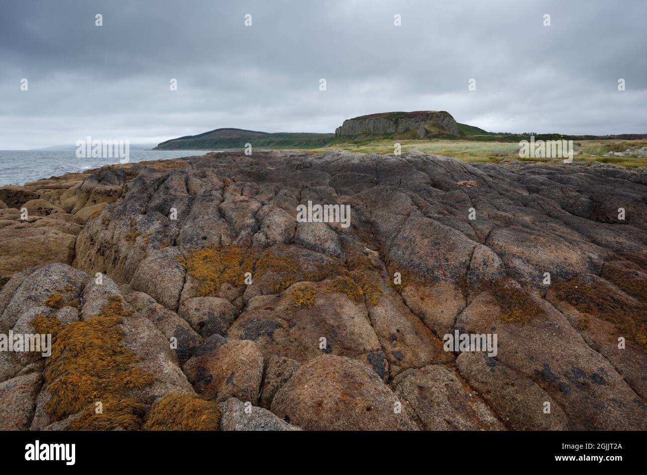 Drumadoon Point. Isle of Arran. Scotland, UK. Volcanic (igneous) geology on the foreshore and in the distant sills. Stock Photo