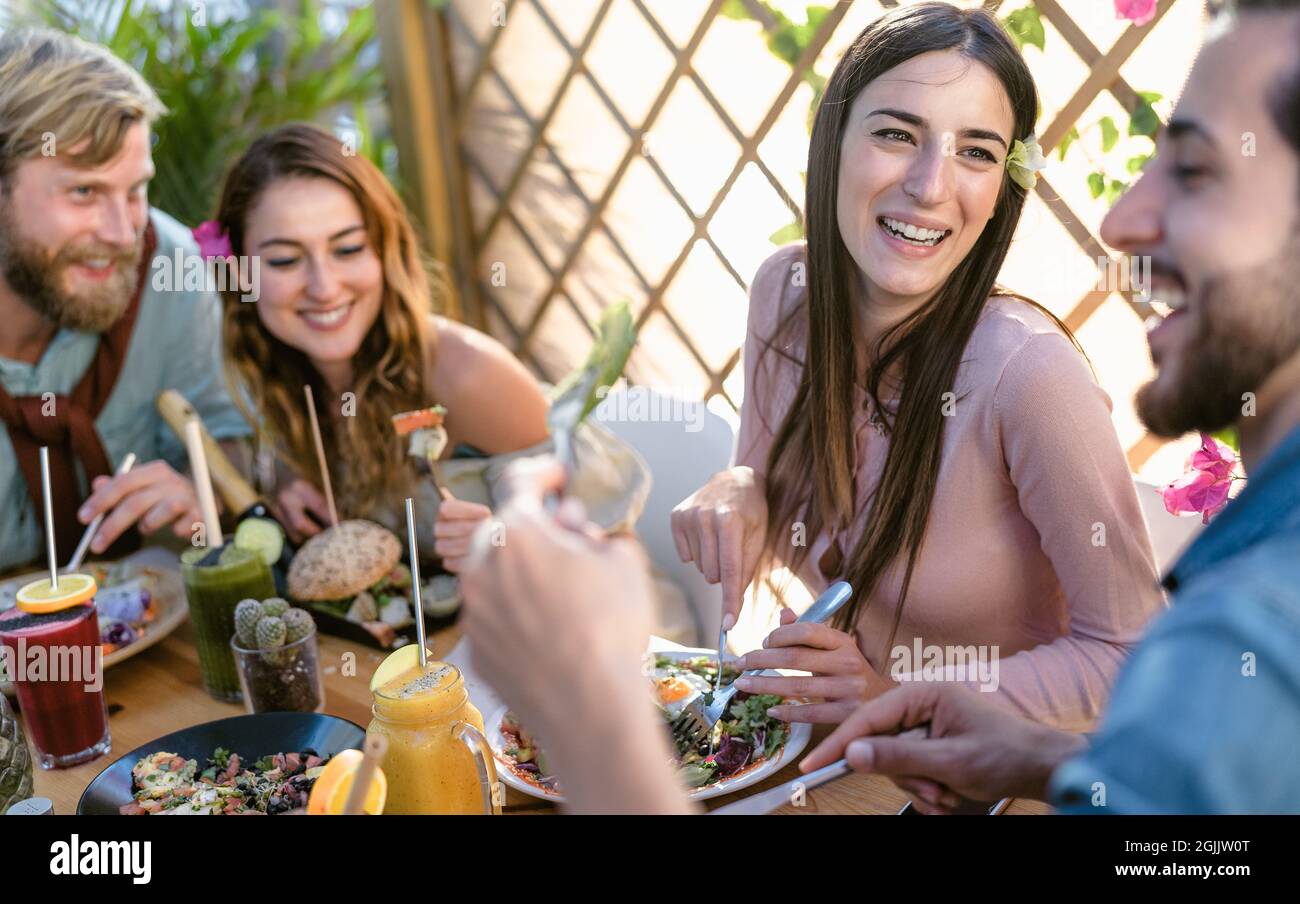 Happy young friends eating healthy lunch and drinking fresh smoothies in cafe brunch restaurant - Health nutrition lifestyle concept Stock Photo