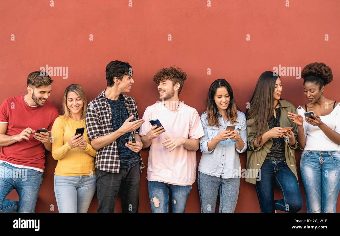 Young friends using mobile smartphone outdoor - Millennial generation having fun with new trends social media apps Stock Photo