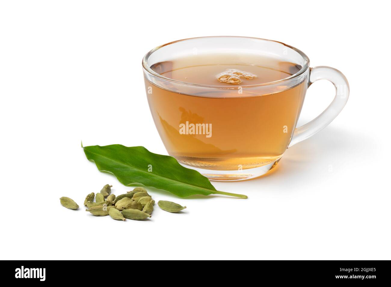 Glass cup with Cardamom tea and a heap with cardamom seeds and leaf in ...