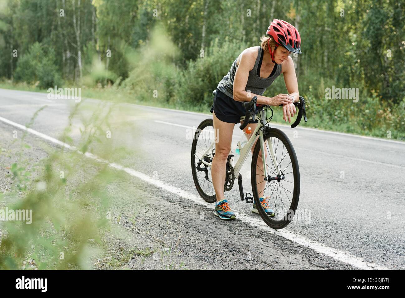 Athlete in helmet checking her fitness bracelet before riding on