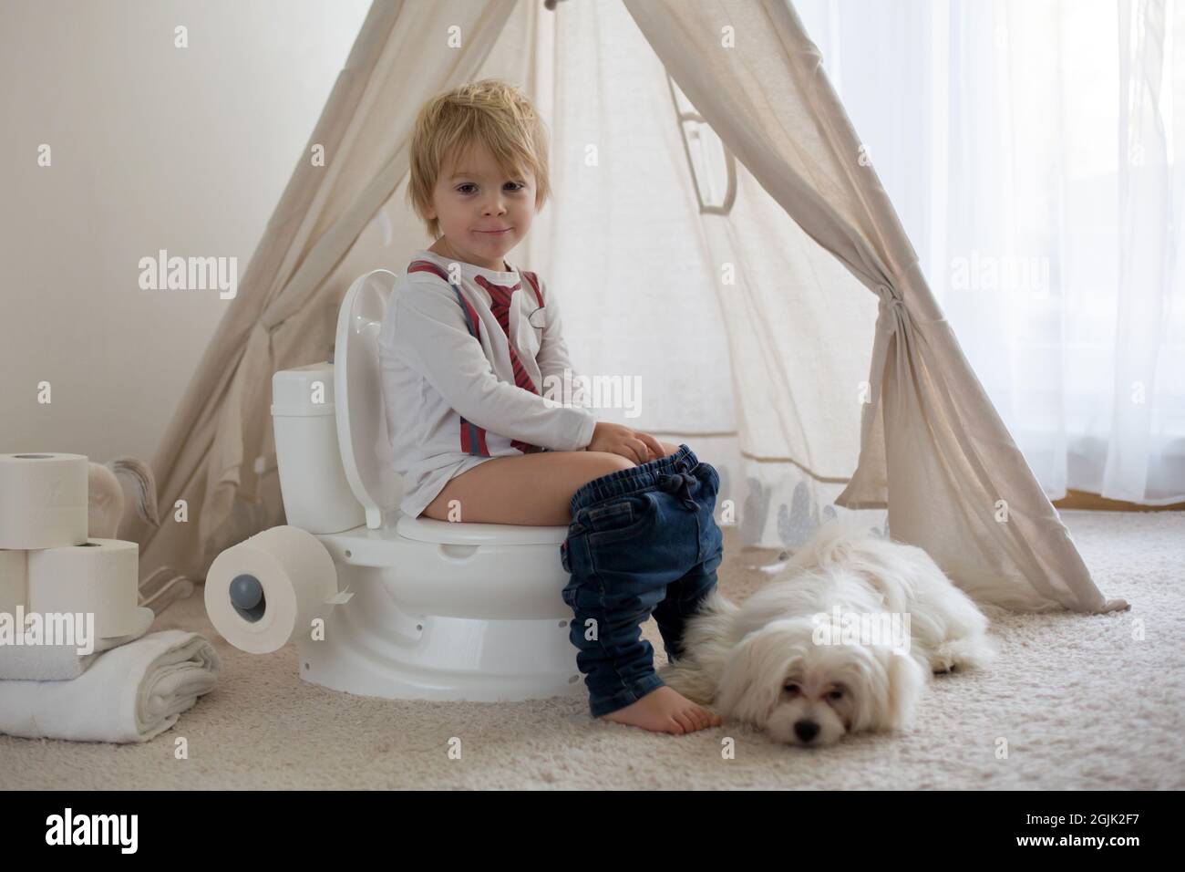 Cute toddler child, boy, sitting on a baby toilet potty, playing with