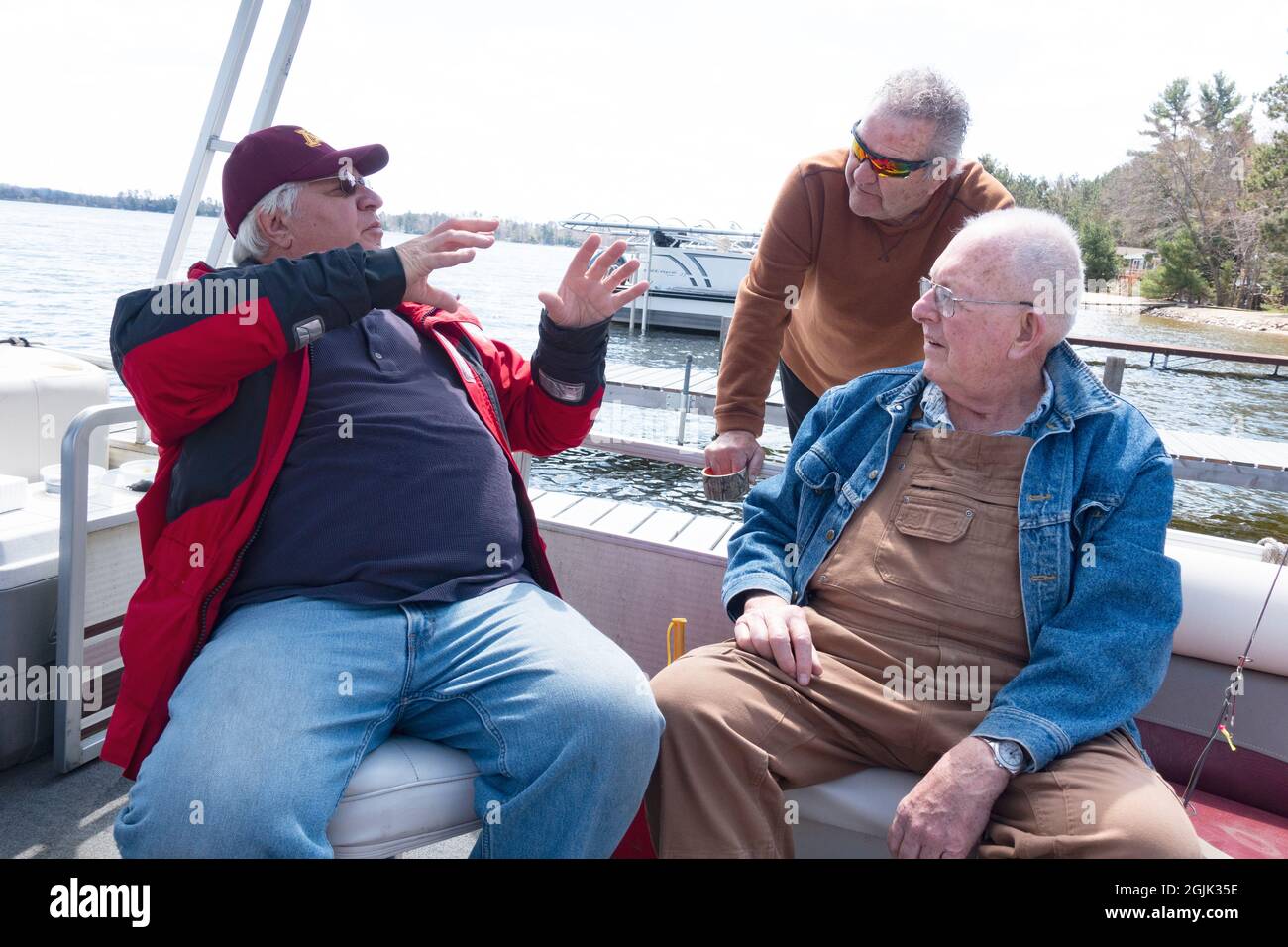 Three senior fisherman discussing plans on a pontoon boat moored to the dock on Gull Lake. Nisswa Minnesota MN USA Stock Photo