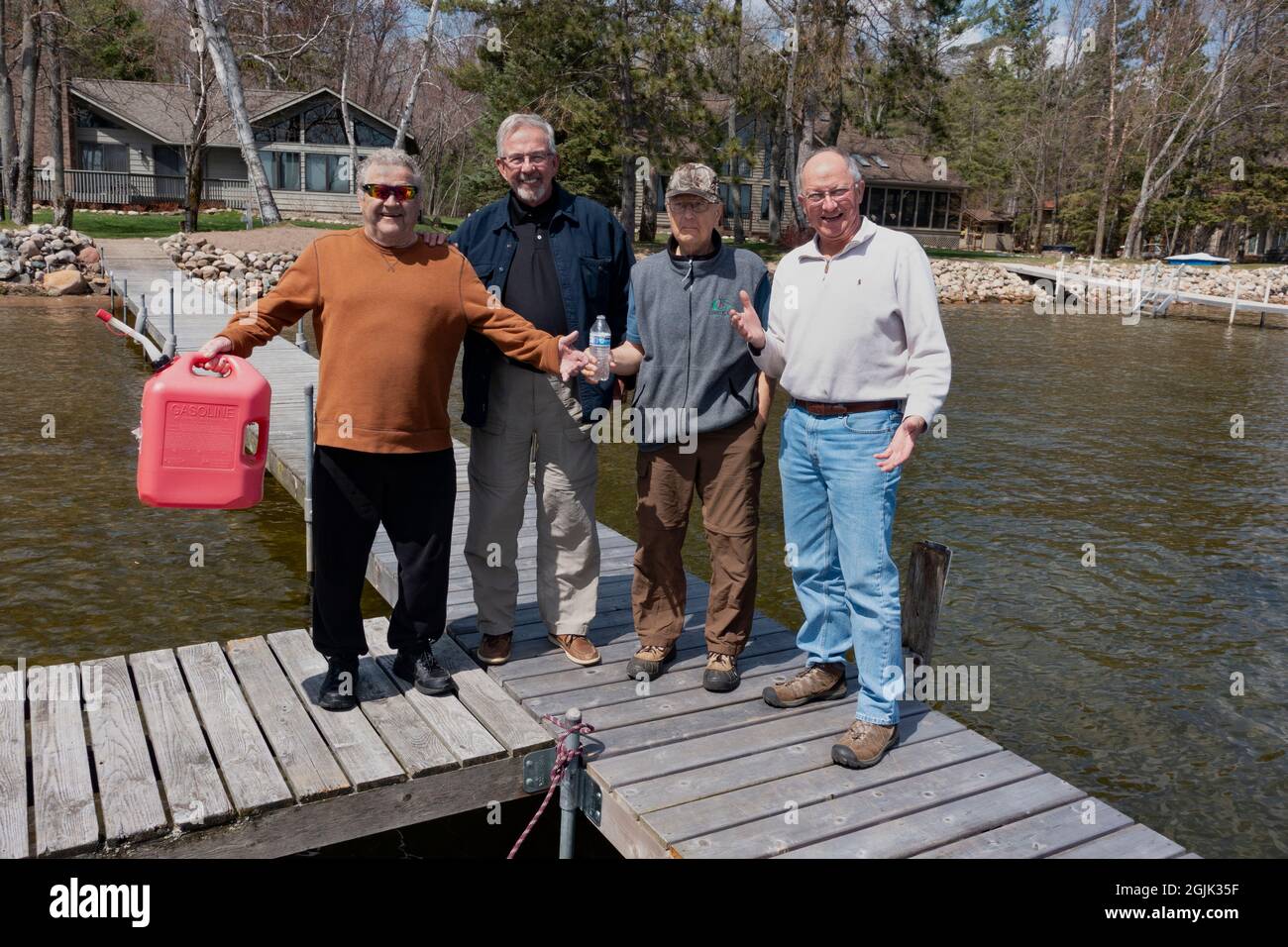 Four senior fishermen on the dock preparing for a fishing trip on Gull Lake holding gas can and water bottle. Nisswa Minnesota MN USA Stock Photo