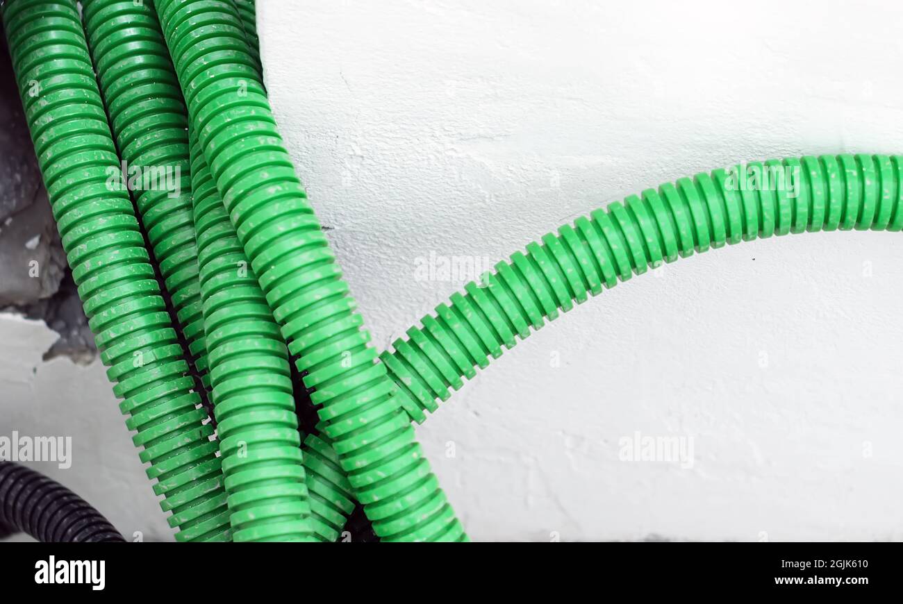 Corrugated tubular conduits ready to be filled with electrical cables on a construction site. White wall in the background. Construction material for Stock Photo