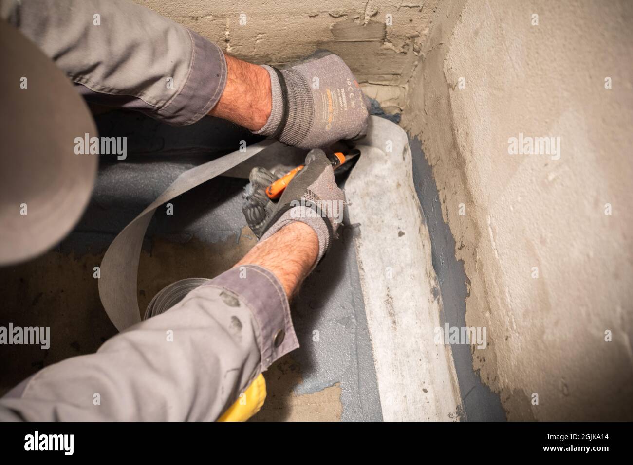 Applying a waterproofing tape to the joint between the wall and the