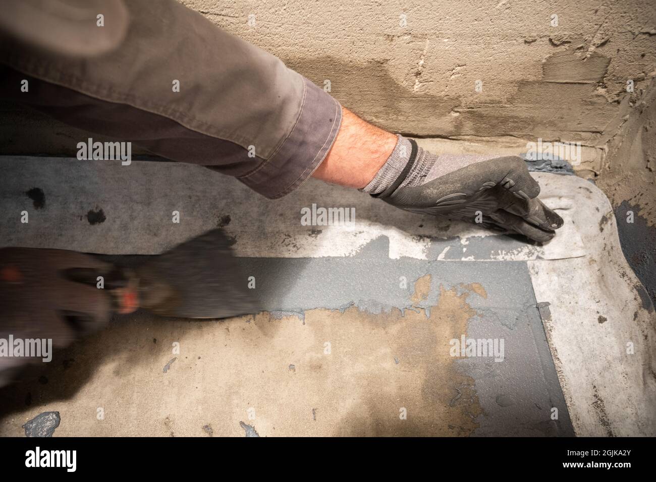 Applying a waterproofing tape to the joint between the wall and the