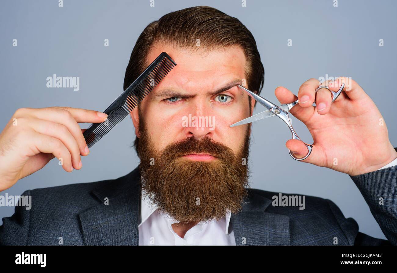 Bearded man with Scissors and comb. Hairdresser with barber tools. Male stylist in barber shop. Beauty and hair salon. Stock Photo