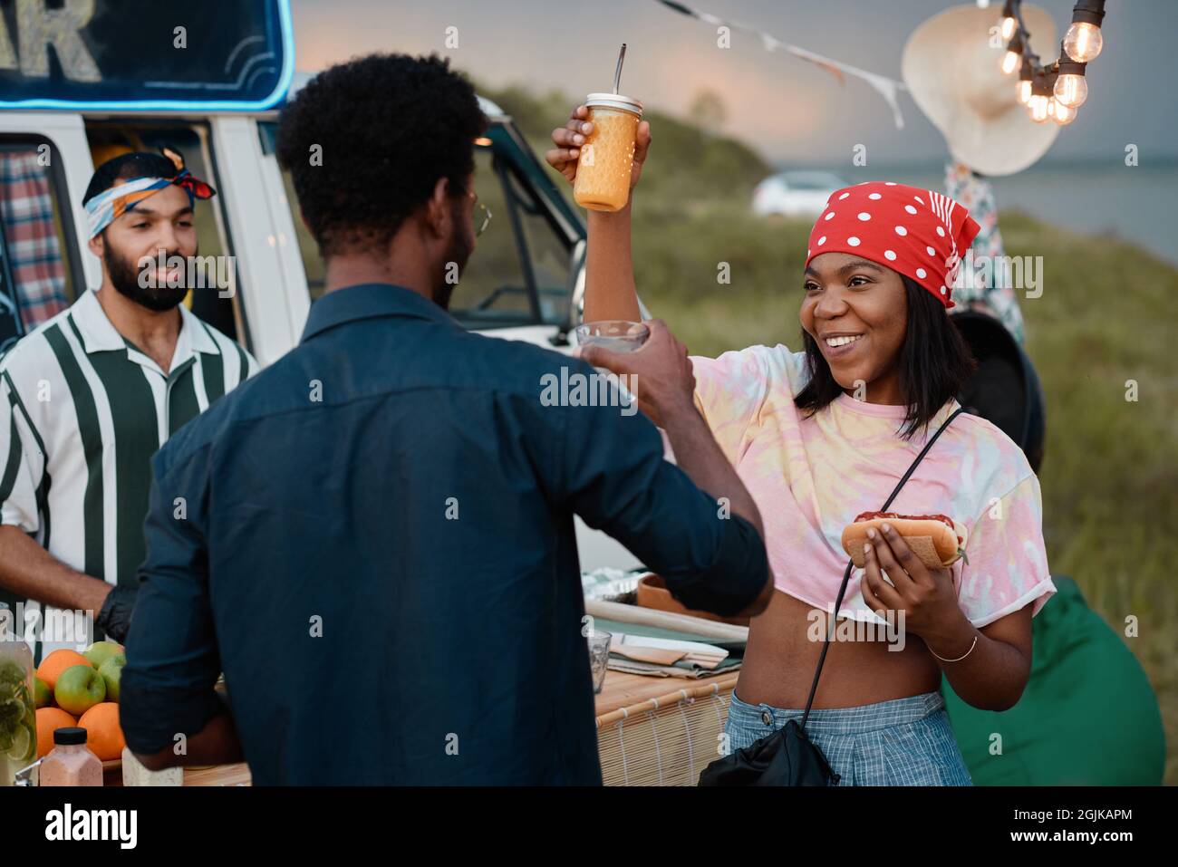 African happy couple eating fast food and dancing during party outdoors
