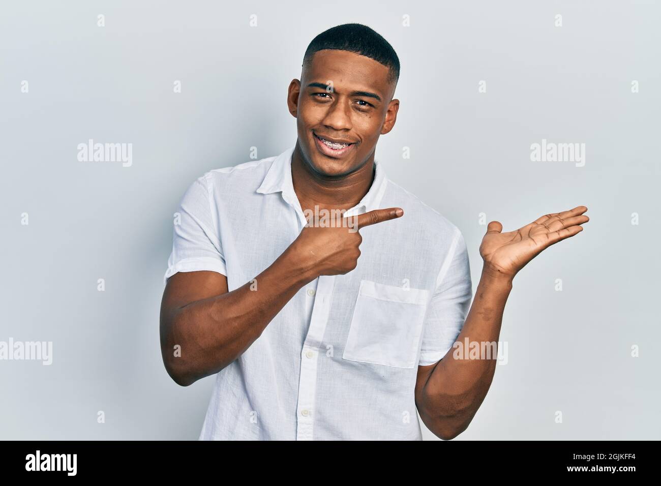 Young black man wearing casual white shirt amazed and smiling to the ...