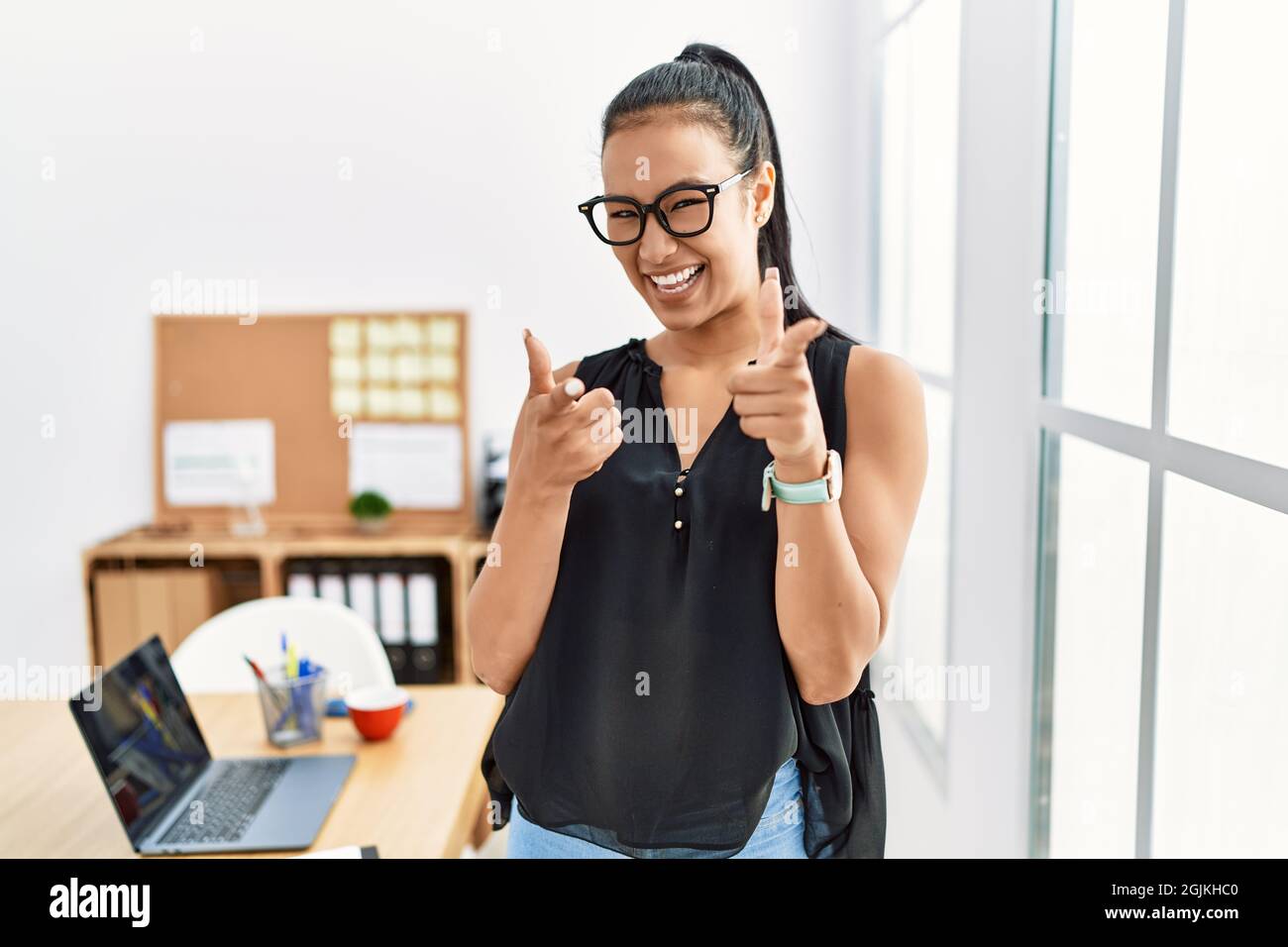 Young hispanic business woman working at the office pointing fingers to ...