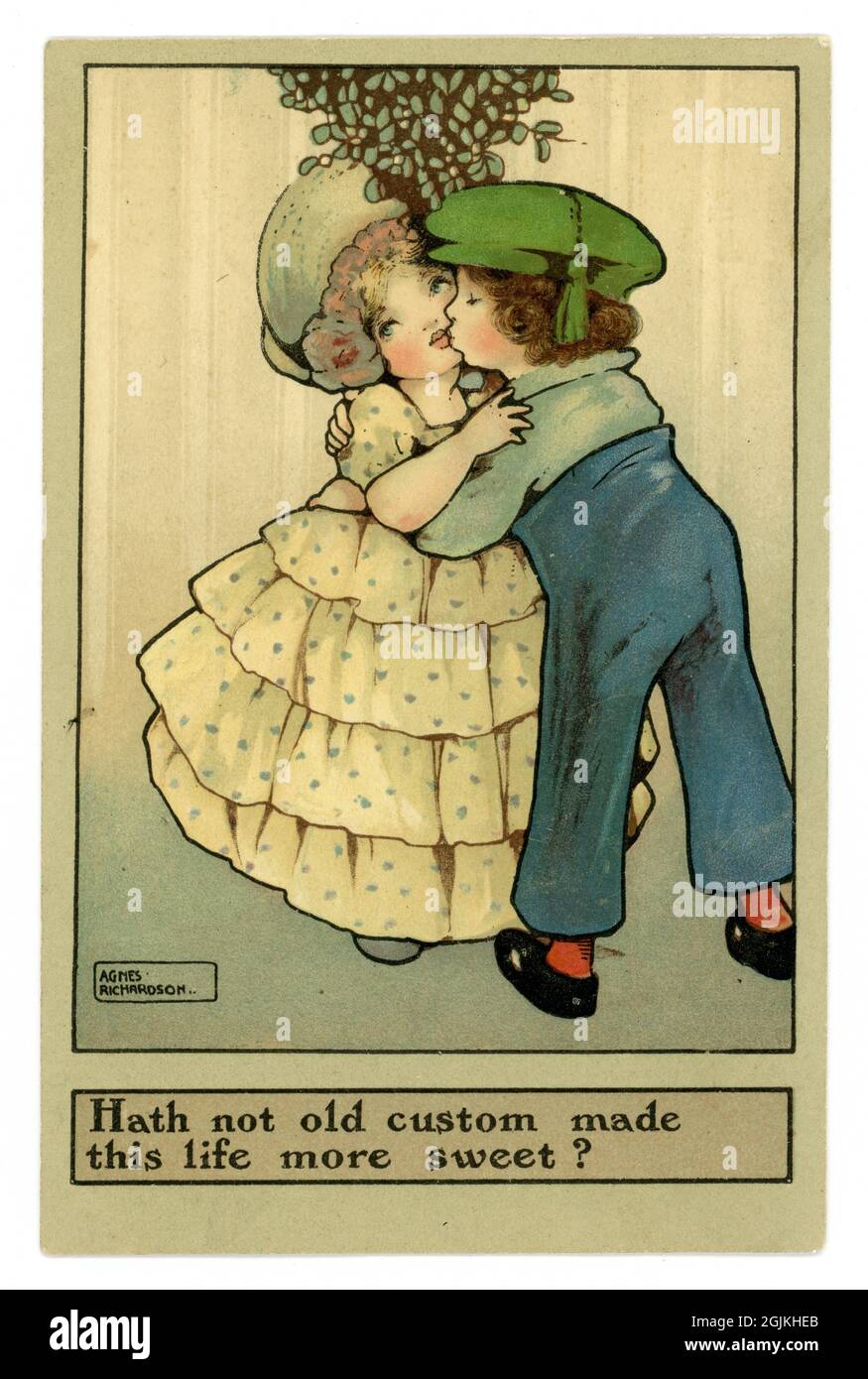 Original charming early 1900's WW1 era sentimental illustrated Christmas Greetings postcard, boy and girl kissing under mistletoe by famous British female children's book illustrator Agnes Richardson, circa 1917 U.K. Stock Photo