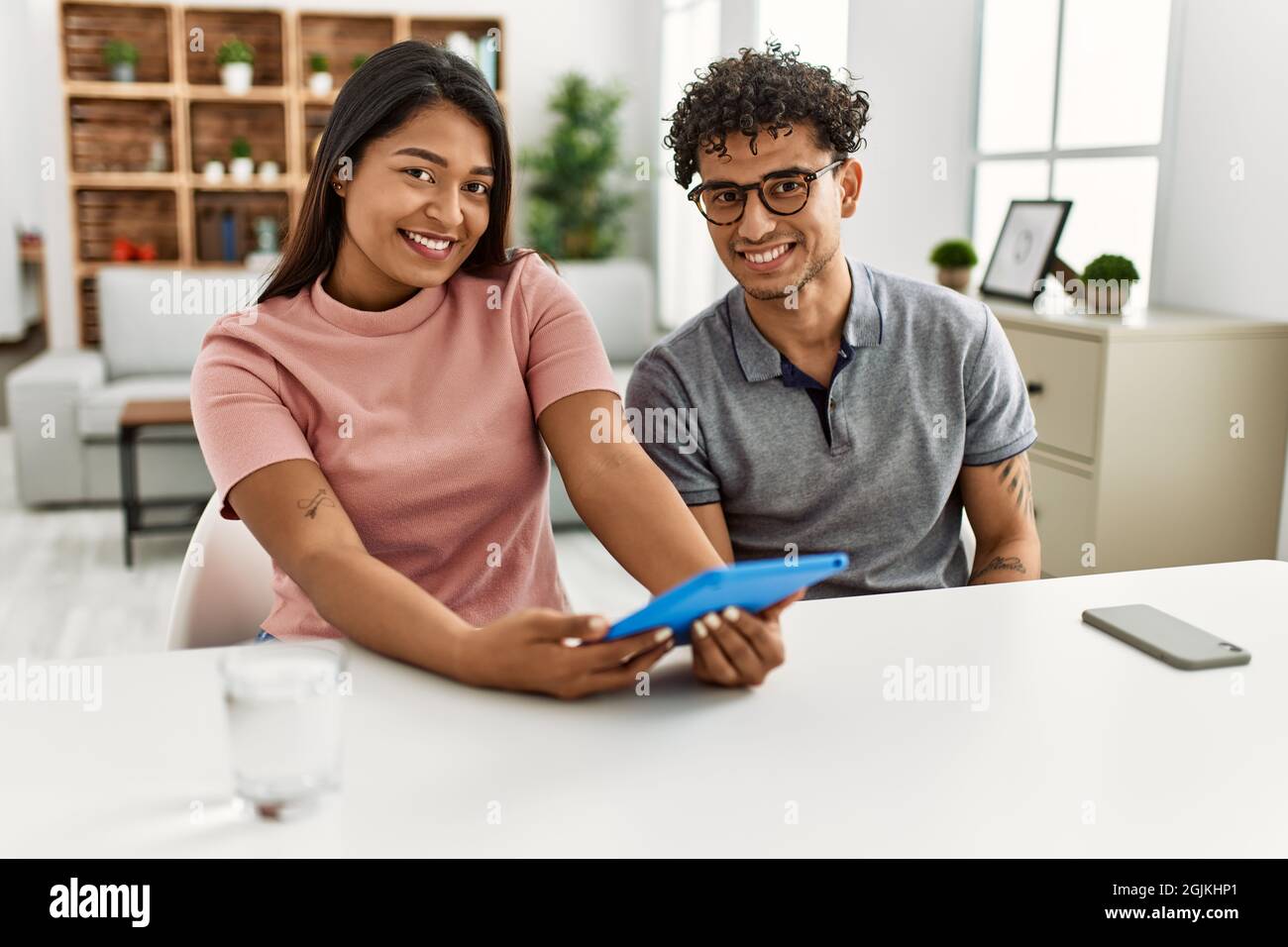 Young latin couple smiling happy using touchpad sitting on the sofa at ...