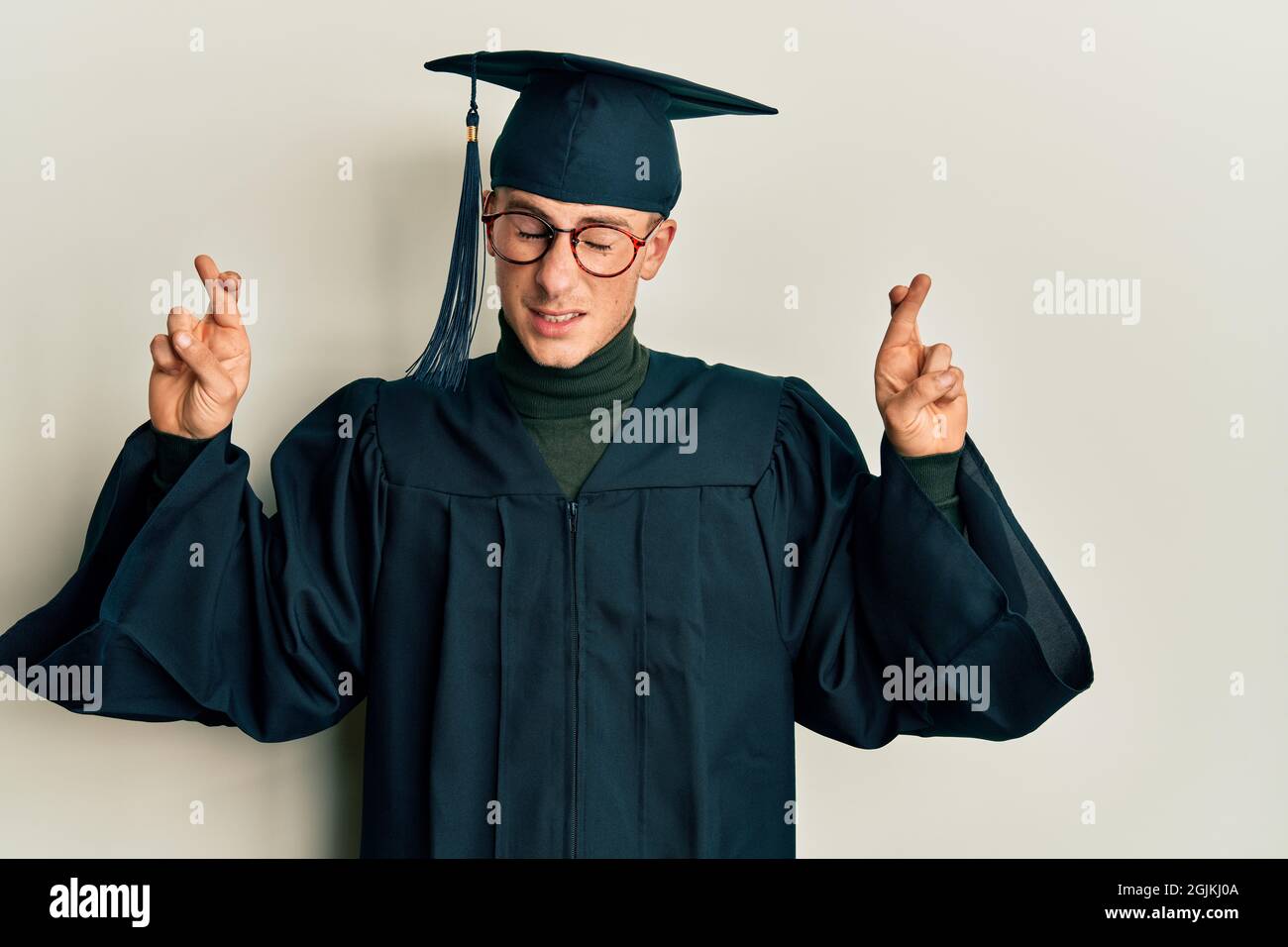 Young caucasian man wearing graduation cap and ceremony robe gesturing ...