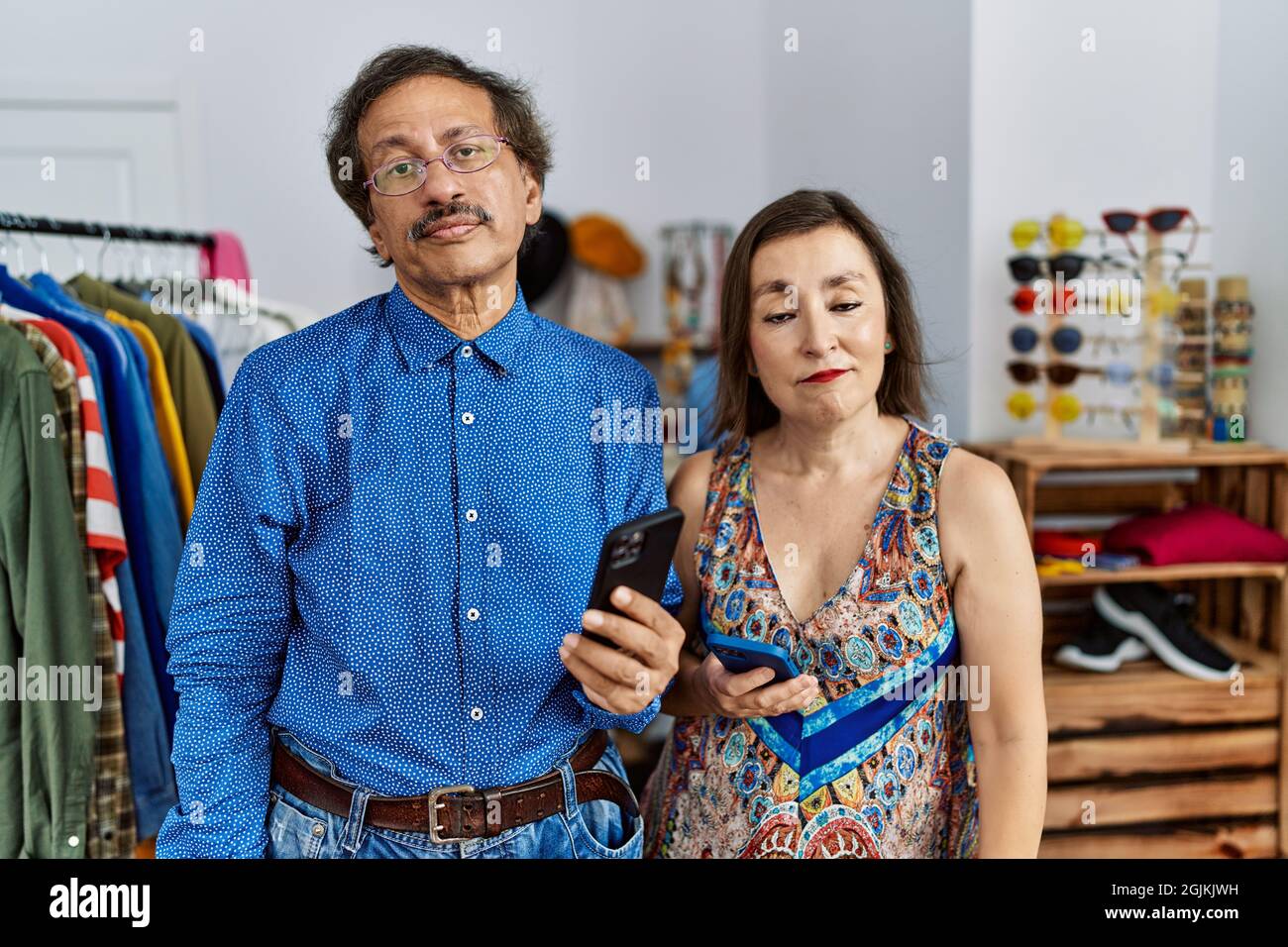 Middle age interracial couple at retail shop using smartphone looking sleepy and tired, exhausted for fatigue and hangover, lazy eyes in the morning. Stock Photo