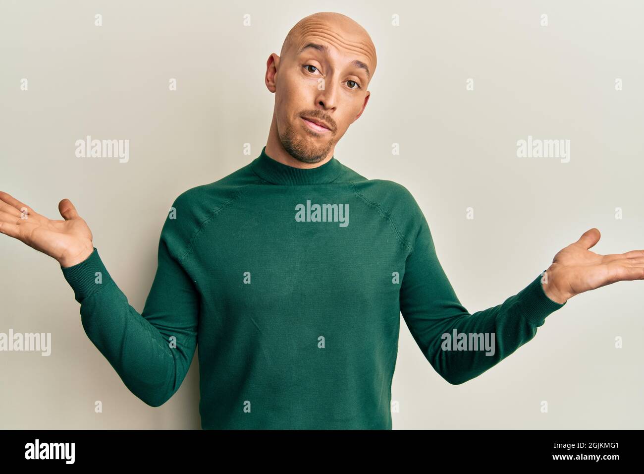 Bald man with beard wearing casual turtleneck sweater clueless and confused with open arms, no idea and doubtful face. Stock Photo