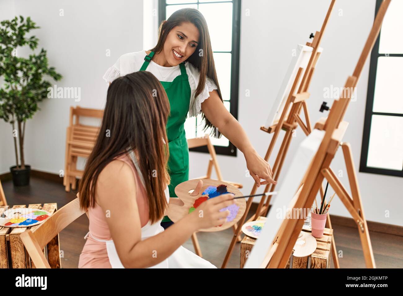 Student and teacher smiling happy painting at art school Stock Photo ...