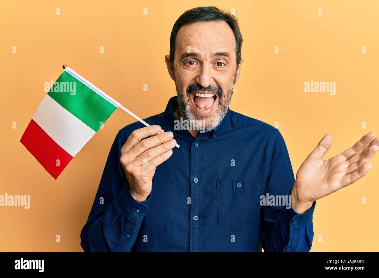 Middle age hispanic man holding italy flag celebrating achievement with happy smile and winner expression with raised hand Stock Photo