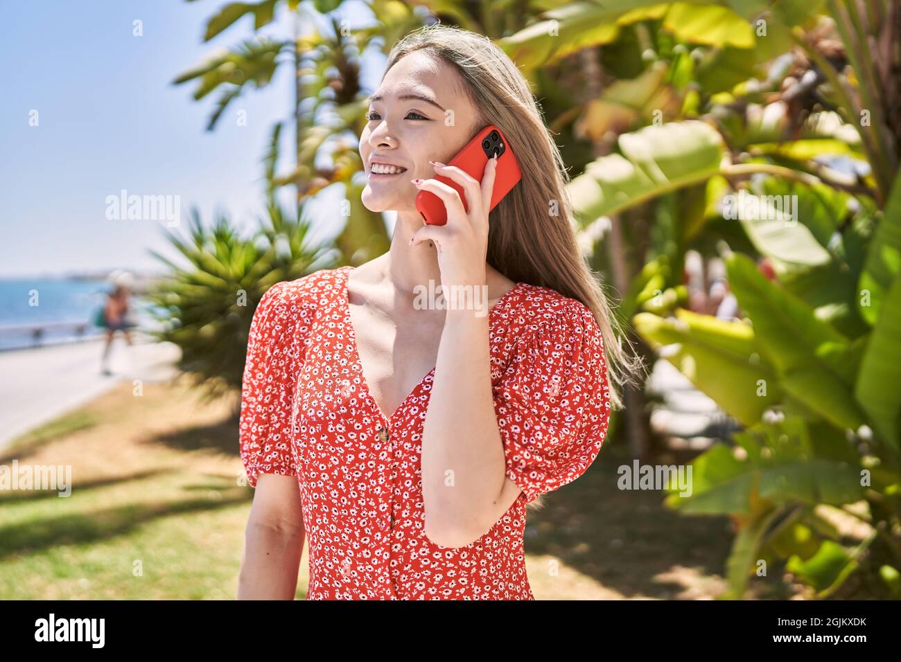 young chinese girl smiling happy talking on the smartphone at the promenade. Stock Photo