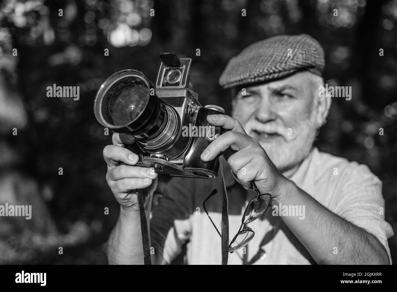 He likes birdwatching. Make perfect frame. Old photographer filming. Manual settings. Pension hobby. Experienced photographer. Vintage camera. Old man Stock Photo