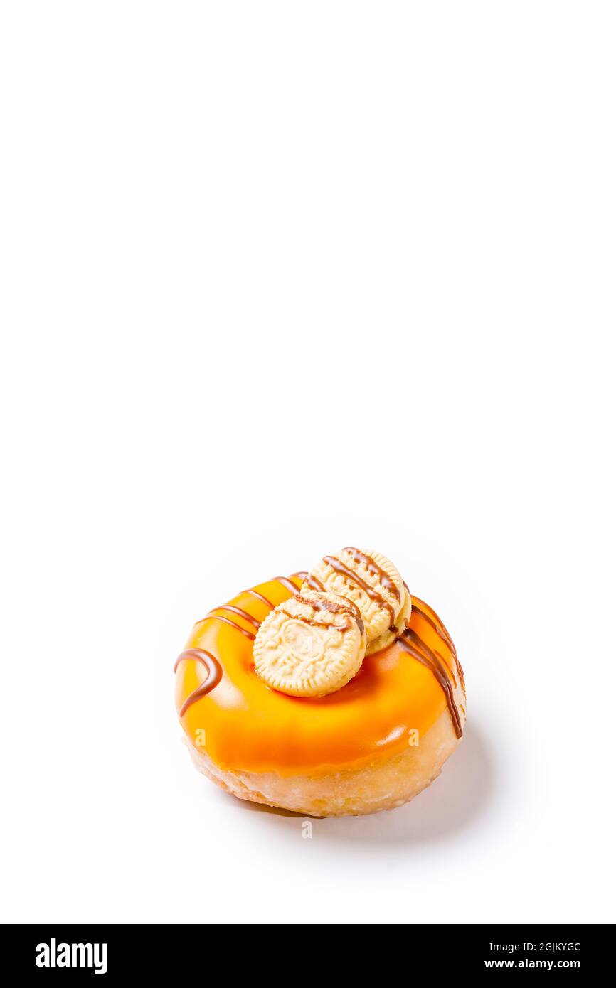 Photograph of a cream donuts painted with chocolate and with cookies on a white background.The photo is taken in vertical format and has copy space. Stock Photo