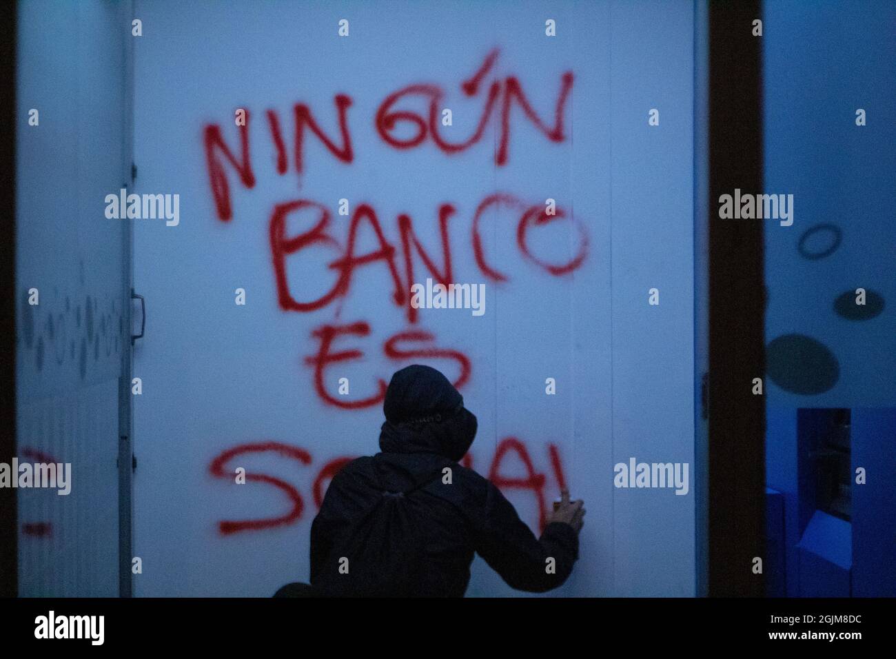 Bogota, Colombia. 10th Sep, 2021. A demonstrator paints a graffiti on a bank wall that reads 'No bank is social' Villa Luz CAI police station were police officers tortured Javier Ordoñez on September 9, 2020, later the same day several police stations were vandalized and burnt due to the death of Ordoñez, and leaving a death toll of 12 other people who died from police firearm use and brutality cases the same night. On September 9, 2021 in Bogota, Colombia. Credit: Long Visual Press/Alamy Live News Stock Photo